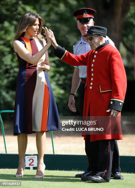 First Lady Melania Trump high-fives with a British military veteran known as a "Chelsea Pensioner" during a game of bowls during a visit to the Royal...