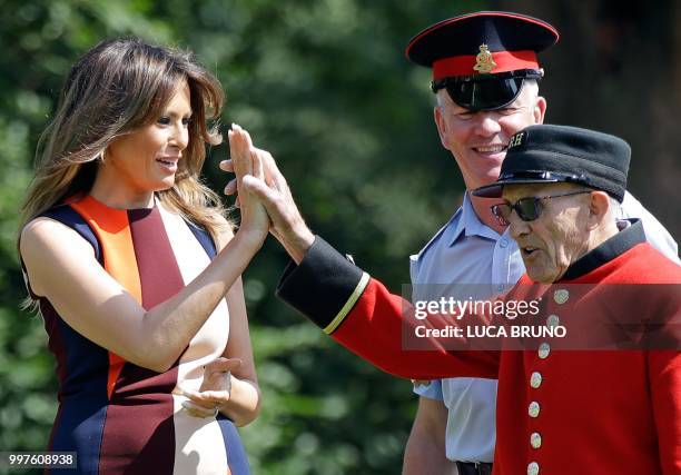 First Lady Melania Trump high-fives with a British military veteran known as a "Chelsea Pensioner" during a game of bowls during a visit to the Royal...