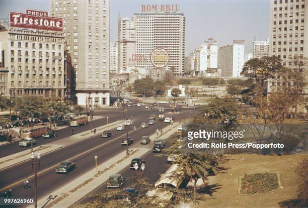 View of cars and buses on a highway boulevard lined with tall buildings and offices in the centre of the Brazilian city of Sao Paulo circa 1965.