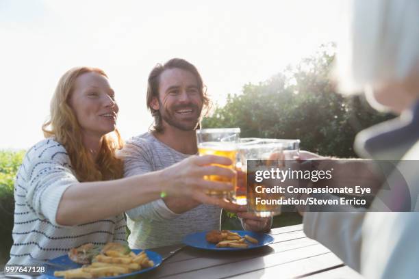 couple and family toasting with beer glasses at campsite picnic table - senior man grey long hair stock pictures, royalty-free photos & images