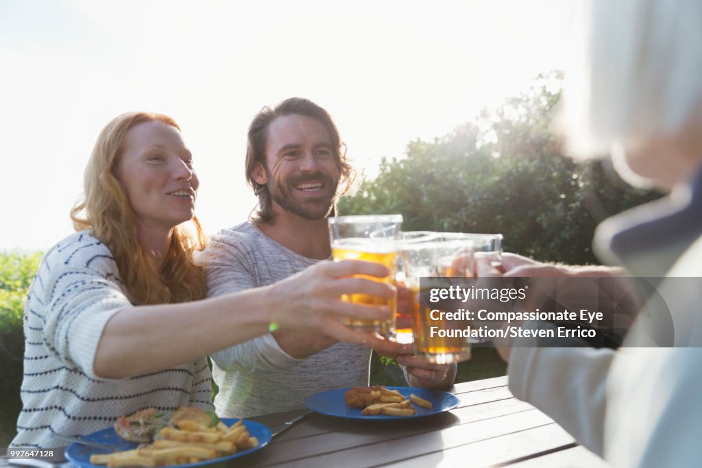 Couple and family toasting with beer glasses at campsite picnic table