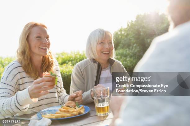 senior woman and family enjoying lunch at campsite picnic table - senior man grey long hair stock pictures, royalty-free photos & images