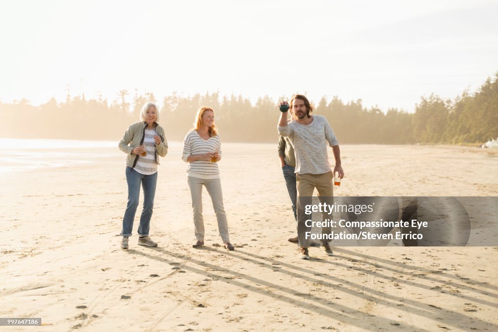 Senior couple and family playing boules on beach at sunset