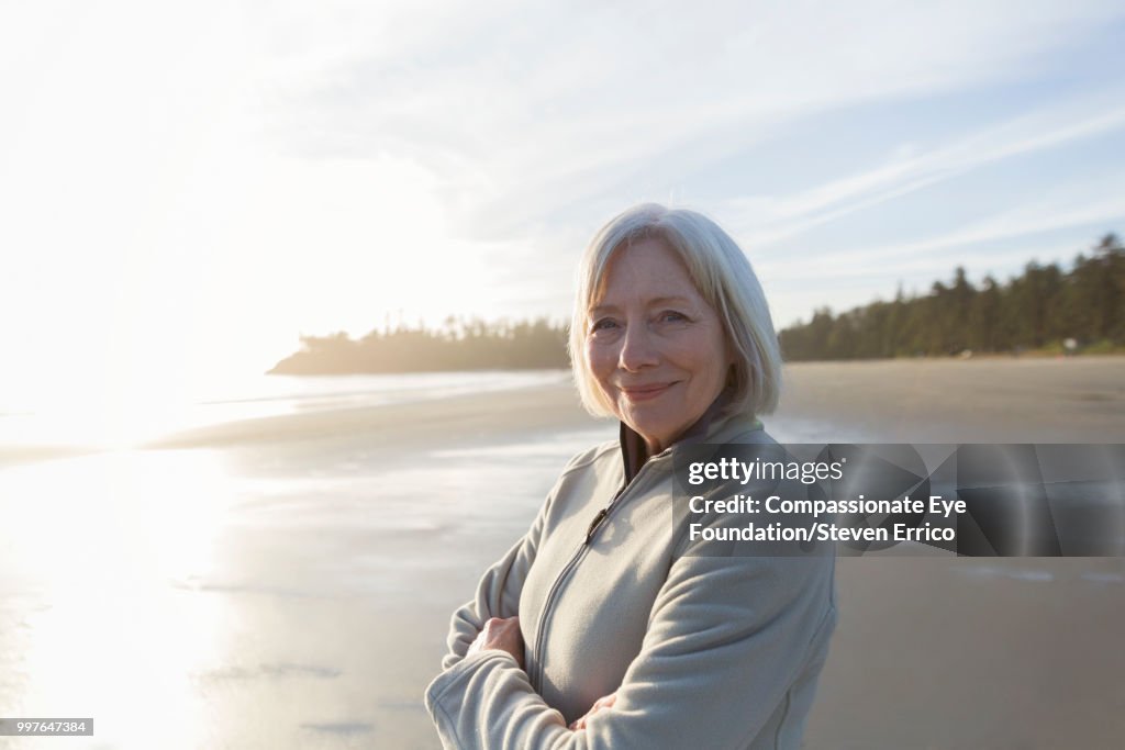 Portrait of smiling senior woman on beach at sunset