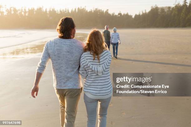 couple walking on beach at sunset - senior man grey long hair stock pictures, royalty-free photos & images