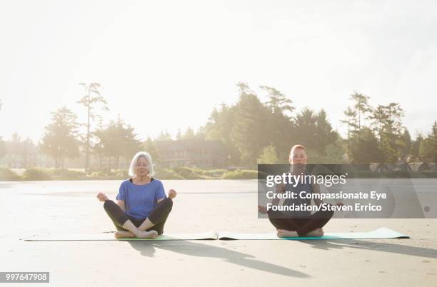 senior woman and daughter practicing yoga on beach - barefoot redhead ストックフォトと画像
