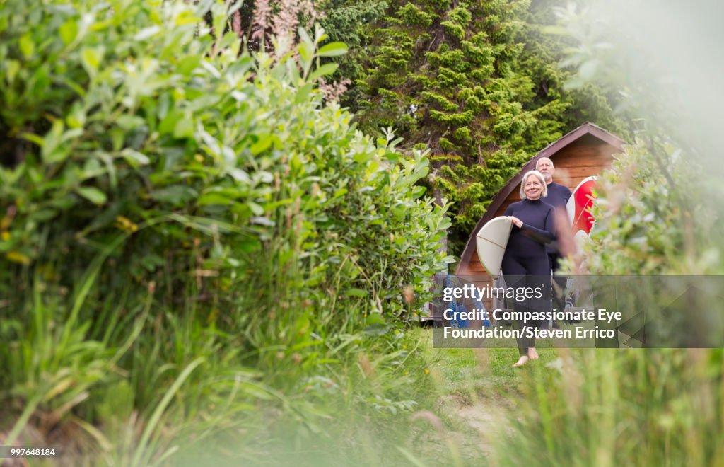 Senior surfers carrying boards on path