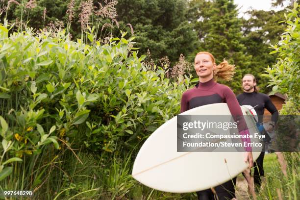 surfers carrying boards on path - compassionate eye foundation stockfoto's en -beelden