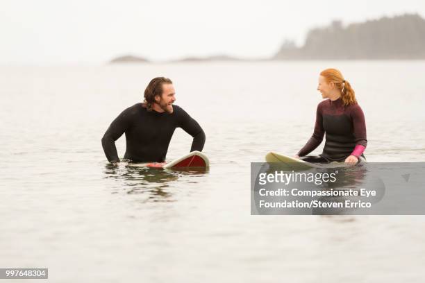 surfers waiting for a wave in sea - "compassionate eye" fotografías e imágenes de stock