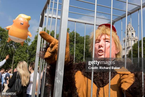 The inflatable balloon called Baby Trump flies above a caged protestor Parliament Square in Westminster, the seat of the UK Parliament, during the US...