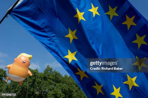 The inflatable balloon called Baby Trump flies above the European Union flag in Parliament Square in Westminster, the seat of the UK Parliament,...