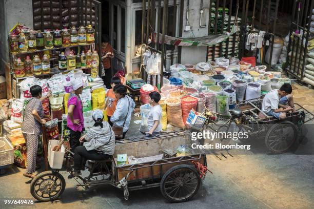 Customers with carts gather round a grain store at a wholesale market in Shanghai, China, on Friday, July 13, 2018. China is scheduled to release...