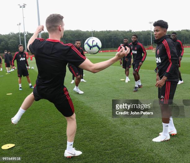 Ethan Hamilton and Demetri Mitchell of Manchester United in action during a first team training session at Aon Training Complex on July 13, 2018 in...