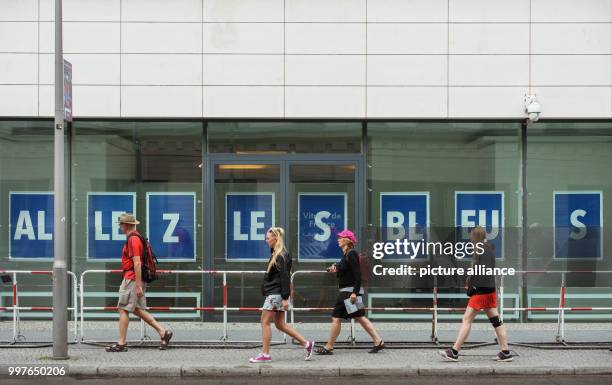 July 2018, Germany, Berlin: Pedestrians walking past big white letters 'Allez les Bleus' on a blue background on the windows of the French emnbassy...