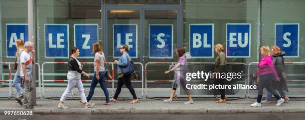 July 2018, Germany, Berlin: Pedestrians walking past big white letters 'Allez les Bleus' on a blue background on the windows of the French emnbassy...