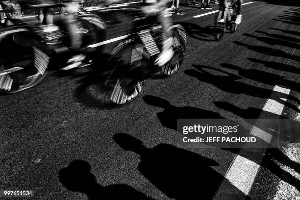 The shadows of spectators are cast on the race's route as riders speeds past during the sixth stage of the 105th edition of the Tour de France...