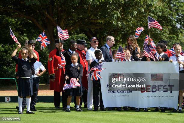Girl wears flags on her head as First Lady, Melania Trump, stands with school children after trying her hand at bowls as she meets British Army...