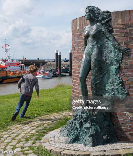 Boy runs around the 'Windsbraut' sculpture on the 'Tag der Seenotretter' in the port of Wilhelmshafen, Germany, 30 July 2017. The annual festival of...