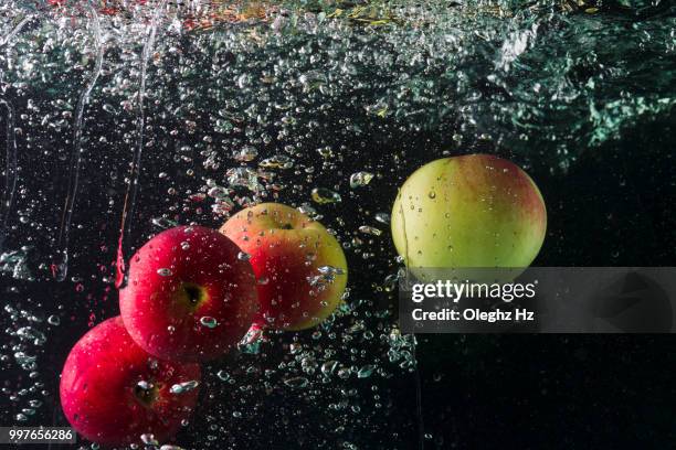 apples in water on a black background - water apples stock pictures, royalty-free photos & images