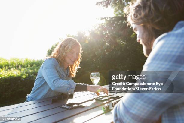 couple playing dominoes at campsite picnic table - compassionate eye foto e immagini stock