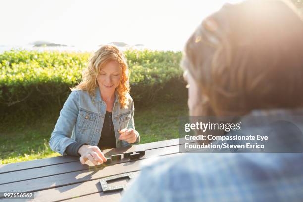 couple playing dominoes at campsite picnic table - compassionate eye foundation stockfoto's en -beelden