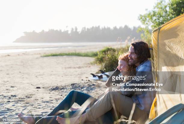 couple sitting on beach looking at ocean view - "compassionate eye" fotografías e imágenes de stock