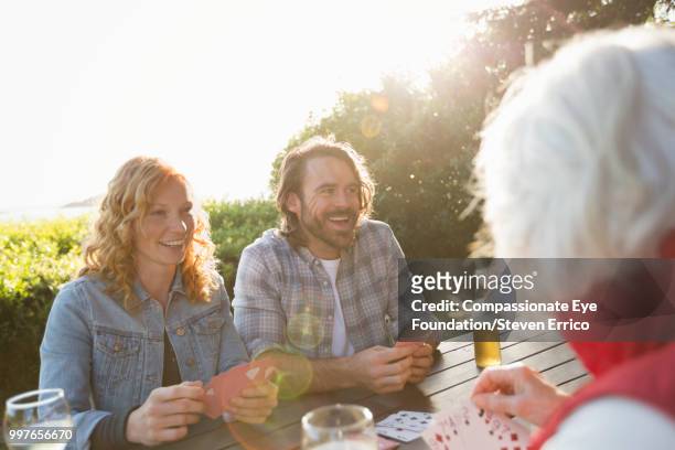 senior woman and adult children playing cards at campsite picnic table - compassionate eye stockfoto's en -beelden