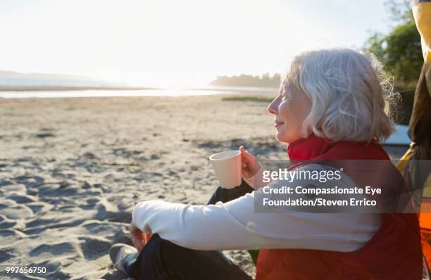 senior woman camping on beach looking at ocean view - cef do not delete stock pictures, royalty-free photos & images