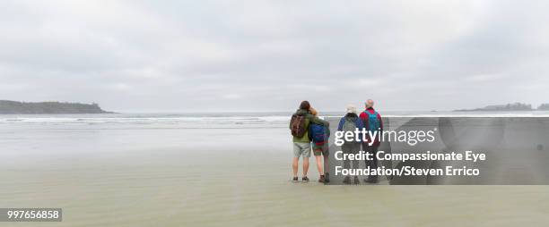 senior couple and adult children hiking on beach looking at ocean view - cef 個照片及圖片檔