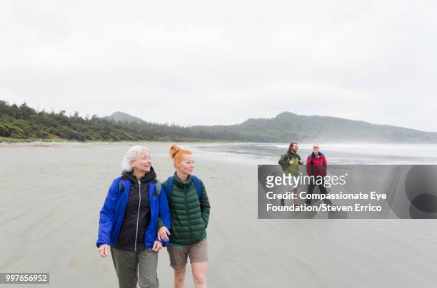 senior couple and adult children hiking on beach - "compassionate eye" fotografías e imágenes de stock