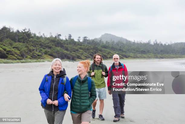 senior couple and adult children hiking on beach - compassionate eye foundation stock-fotos und bilder