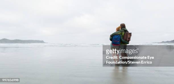 couple hiking on beach looking at ocean view - compassionate eye foundation imagens e fotografias de stock