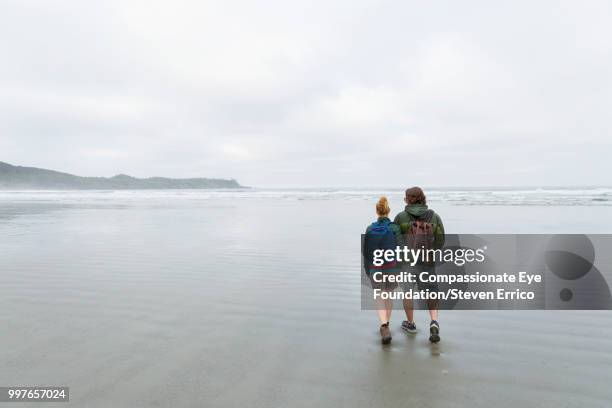 couple hiking on beach - compassionate eye foundation stock-fotos und bilder