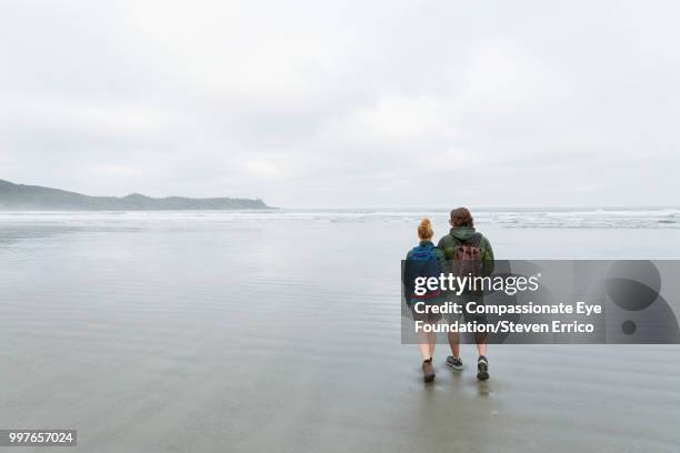 couple hiking on beach - "compassionate eye" fotografías e imágenes de stock