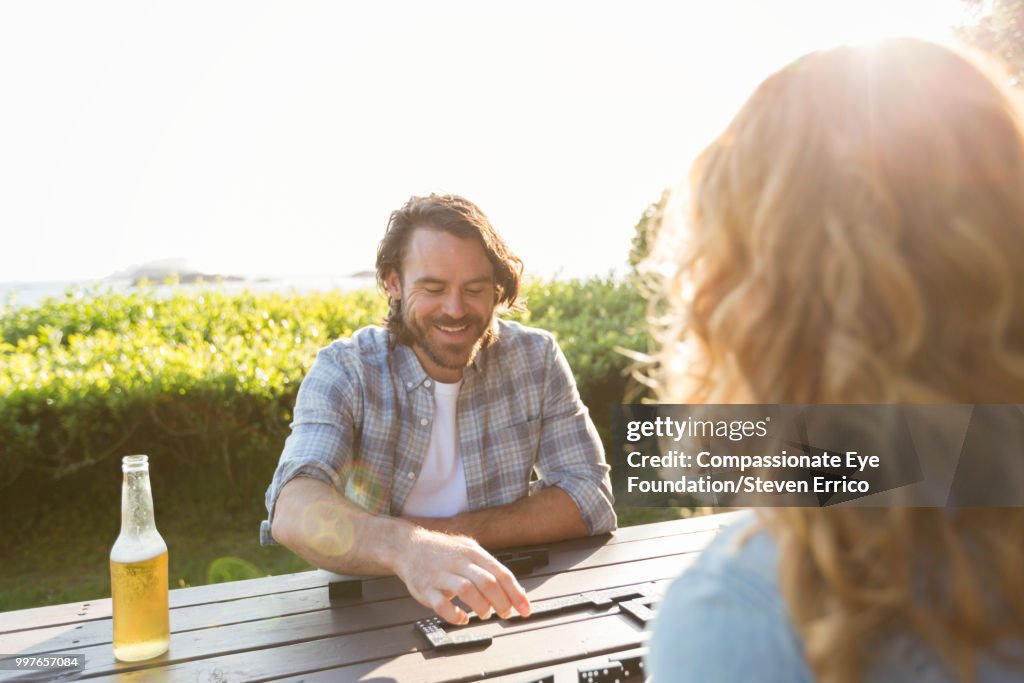 Couple playing dominoes at campsite picnic table