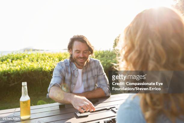 couple playing dominoes at campsite picnic table - cef do not delete stock pictures, royalty-free photos & images
