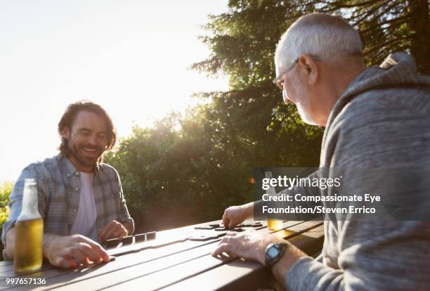 senior man and adult son playing dominoes at campsite picnic table - cef do not delete imagens e fotografias de stock