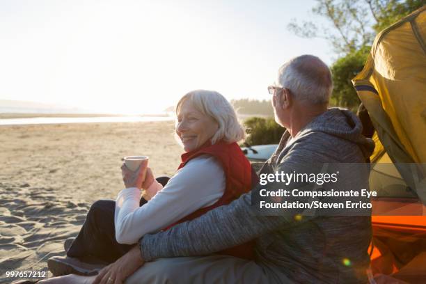 senior couple camping on beach looking at ocean view - "compassionate eye" fotografías e imágenes de stock