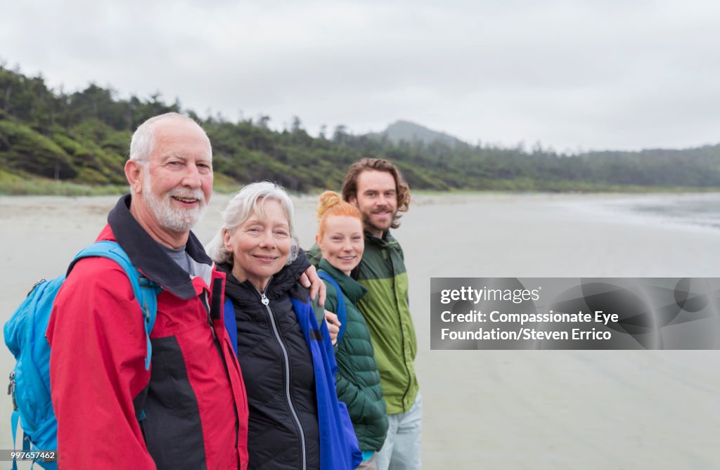 Senior couple and adult children hiking on beach looking at ocean view