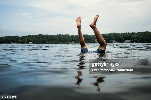 man's feet sticking out of the water in lake - black men feet stock pictures, royalty-free photos & images