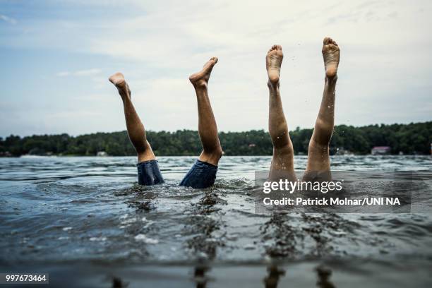 couples feet sticking out of the water in lake - piernas en el aire fotografías e imágenes de stock