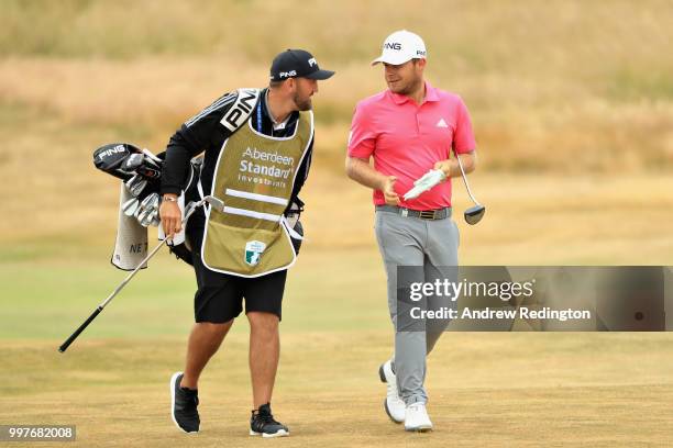 Tyrrell Hatton of England talks with his caddy Mark Crane on hole eighteen during day two of the Aberdeen Standard Investments Scottish Open at...