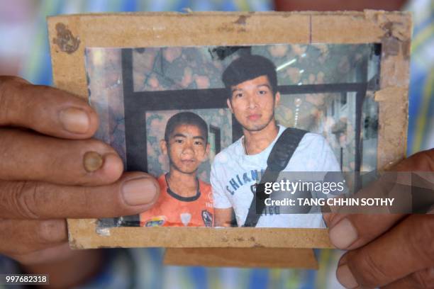 Jai Sutham holds an undated photo of his grandson Prachak Sutham , one of the 12 "Wild Boars" football team recsued this week from a cave, during an...