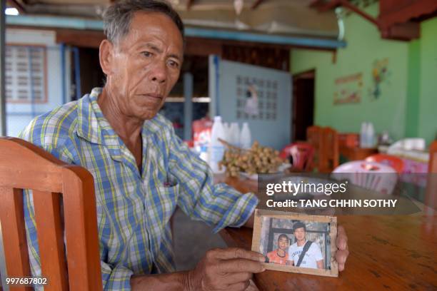 Jai Sutham holds an undated photo of his grandson Prachak Sutham , one of the 12 "Wild Boars" football team recsued this week from a cave, during an...