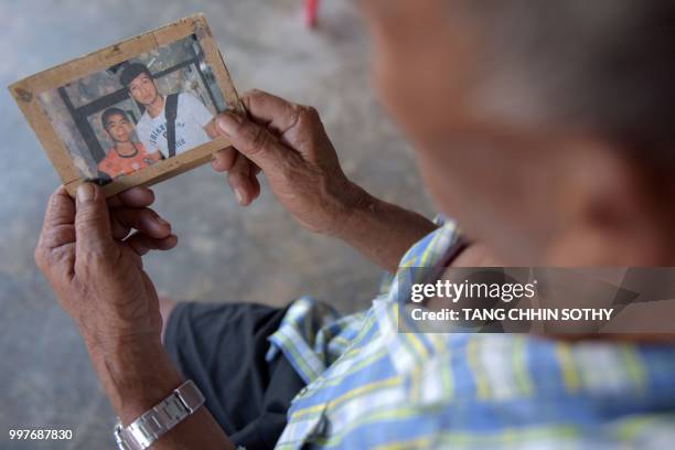 Jai Sutham holds an undated photo of his grandson Prachak Sutham , one of the 12 "Wild Boars" football team recsued this week from a cave, during an...