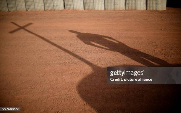 The shadow of a cross can be seen in the red sand of the Camp Castor in Gao, Mali, 30 July 2017. After the fatal helicopter crash in Mali the German...