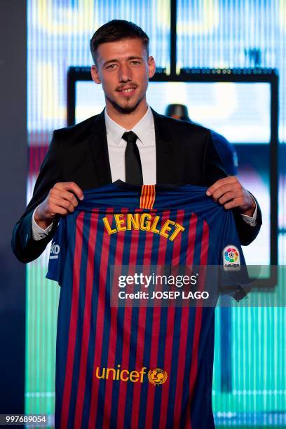 Barcelona's new player French defender Clement Lenglet poses holding his new jersey during his official presentation at the Camp Nou stadium in...