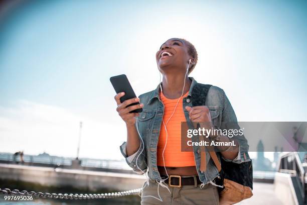 jeune femme tenant le téléphone mobile et écouter de la musique - fashion pretty woman listening music in headphones with smartphone colorful photos et images de collection