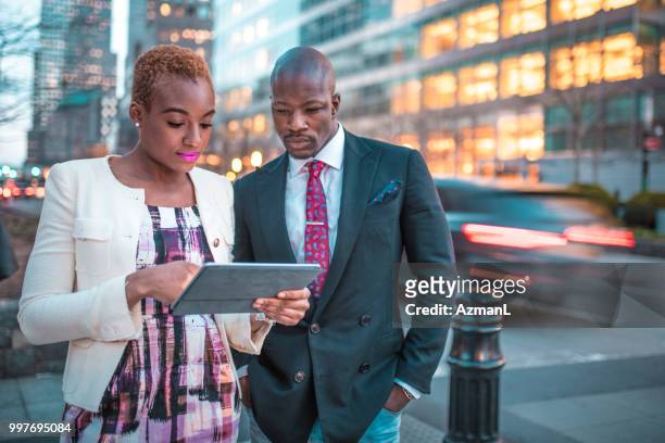 外出先でデジタル タブレットを使用してビジネスマンおよびビジネスの笑顔の女性 - azmanl ストックフォトと画像