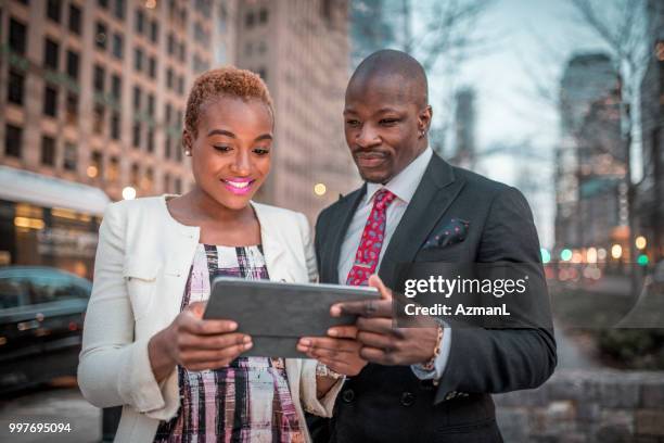 外出先でデジタル タブレットを使用してビジネスマンおよびビジネスの笑顔の女性 - azmanl ストックフォトと画像